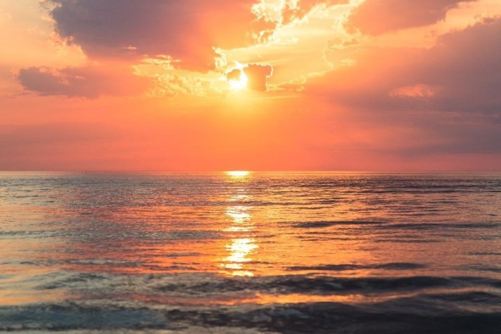 a sunset over a beach next to the ocean