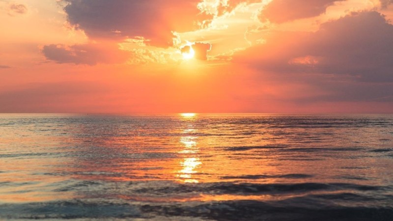 a sunset over a beach next to the ocean