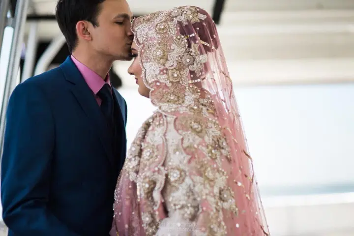 a person wearing a pink dress standing in front of a building