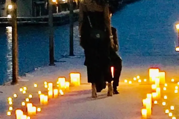 a person standing in front of a birthday cake with lit candles