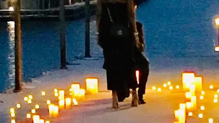 a person standing in front of a birthday cake with lit candles